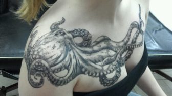 A Black And White Tattoo Of An Octopus Adorns This Grils Chest And Shoulders 336x189